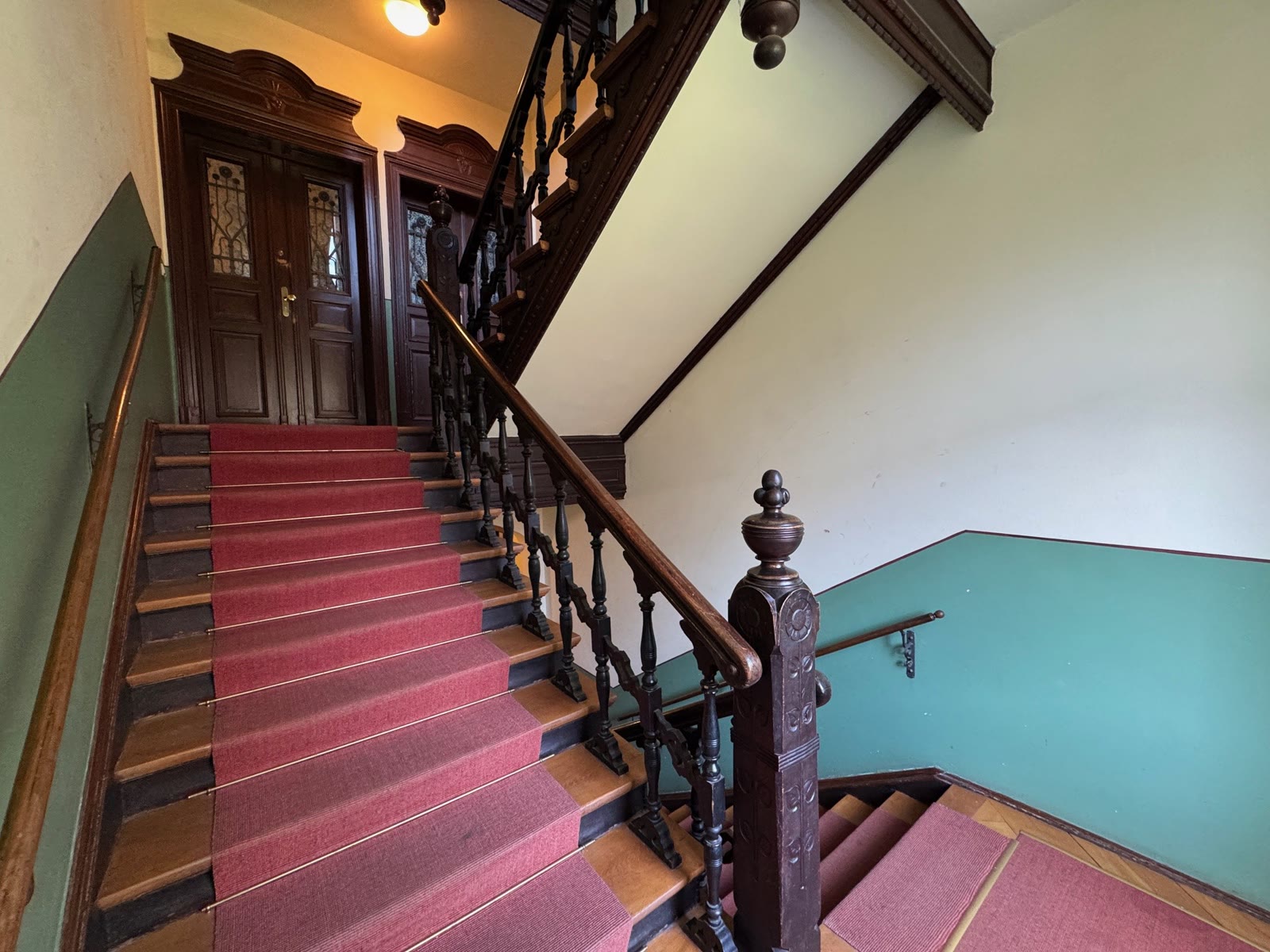 Historisches Treppenhaus mit Holzgeländer und Wohnungstüren
